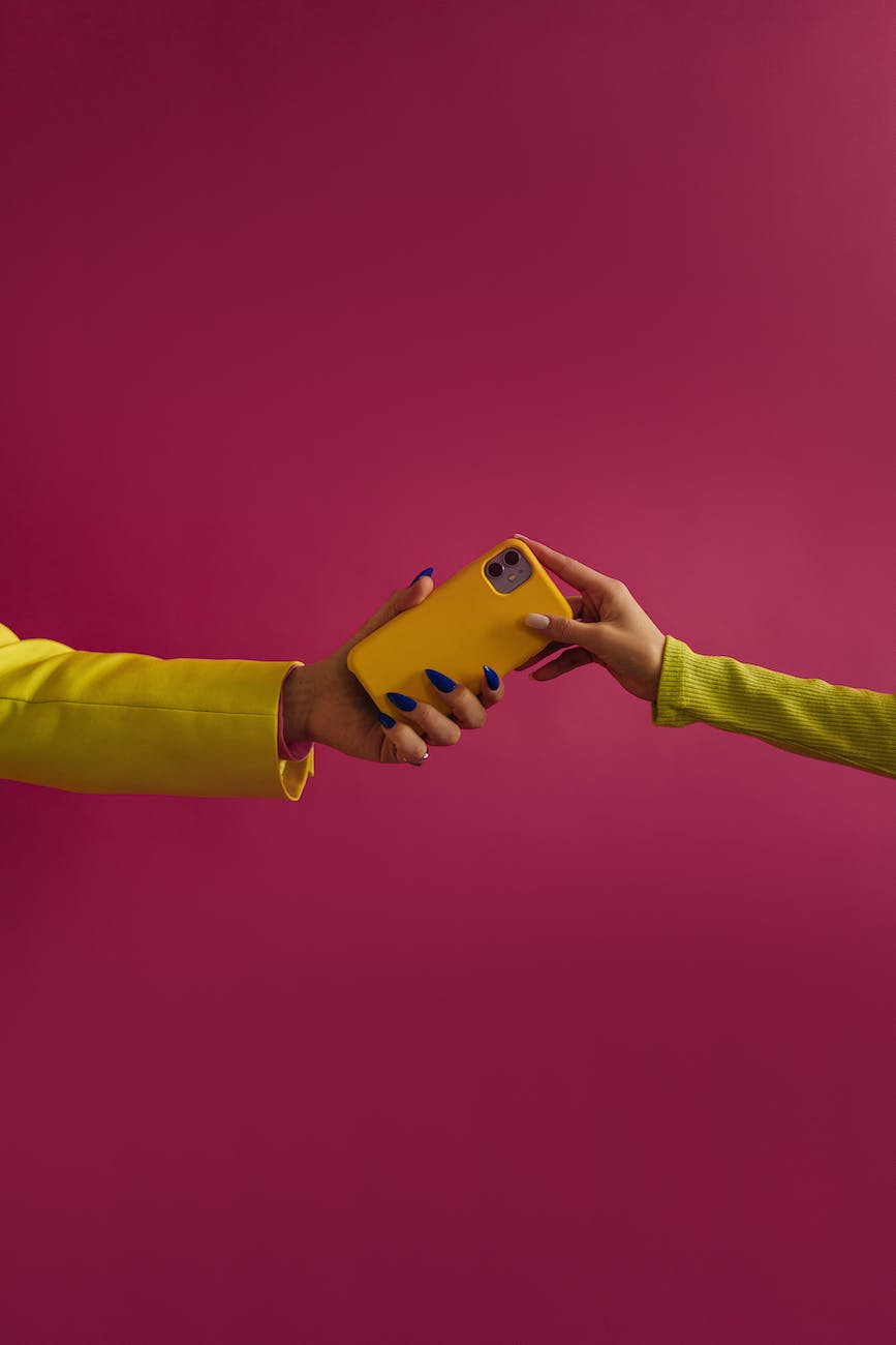 Two unrecognizable female hands holding yellow mobile phone