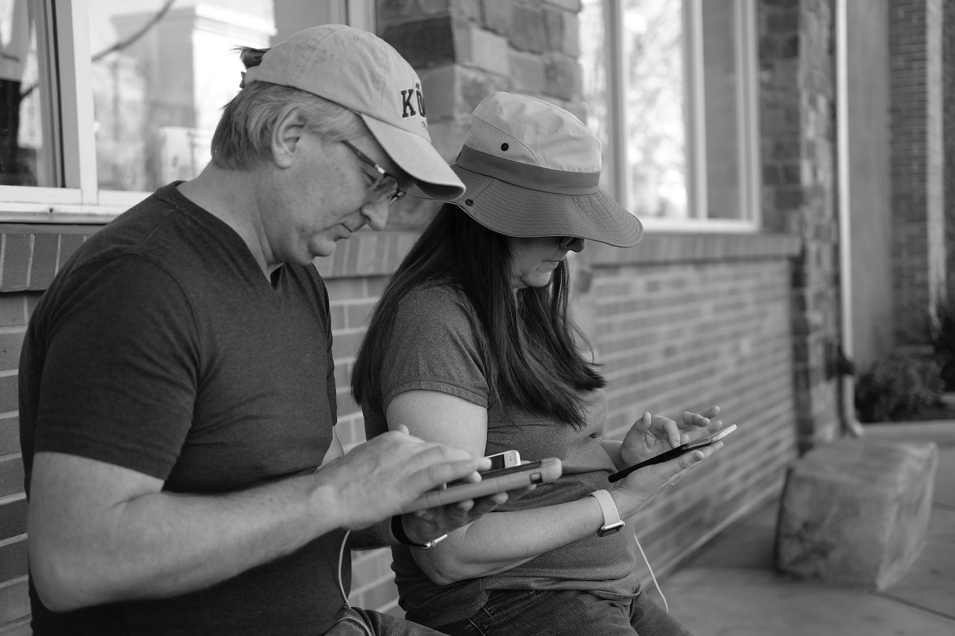 Couple sitting on a bench and using smartphones parenting