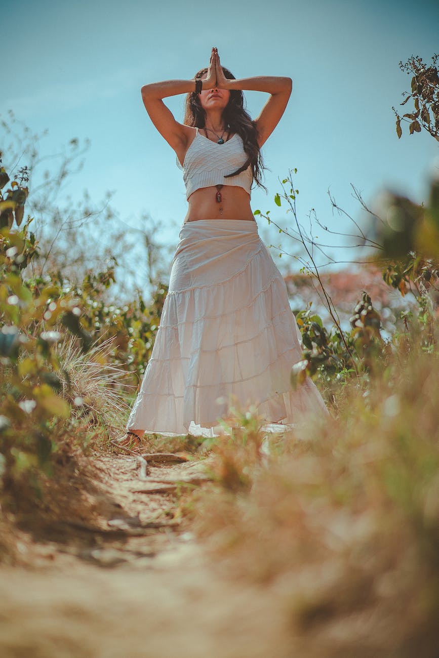 Woman in white tank crop top on grass field yoga sutras