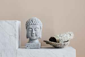 stone buddha and sage incense bundle in bowl on marble shelf ancient rituals