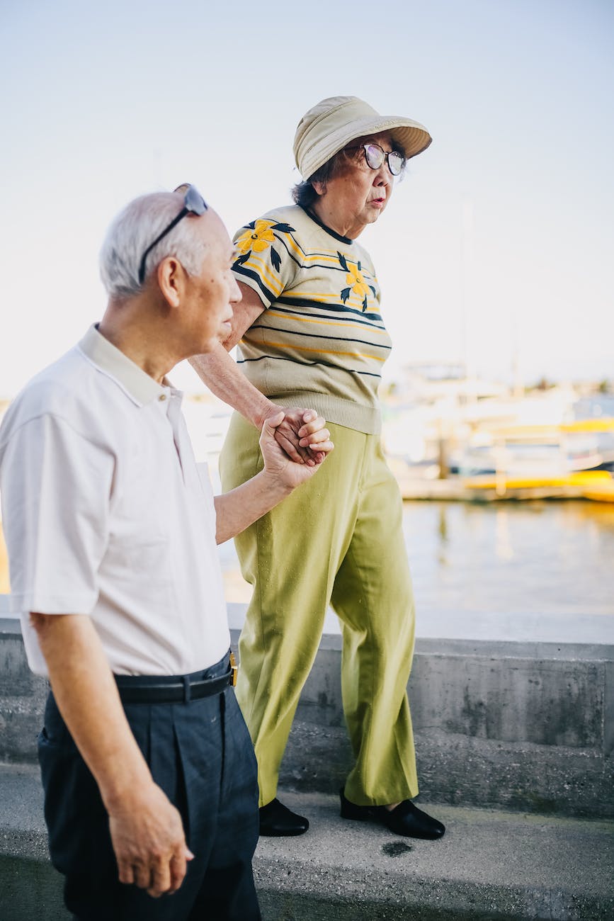 Elderly couple walking by the bay hold hands
