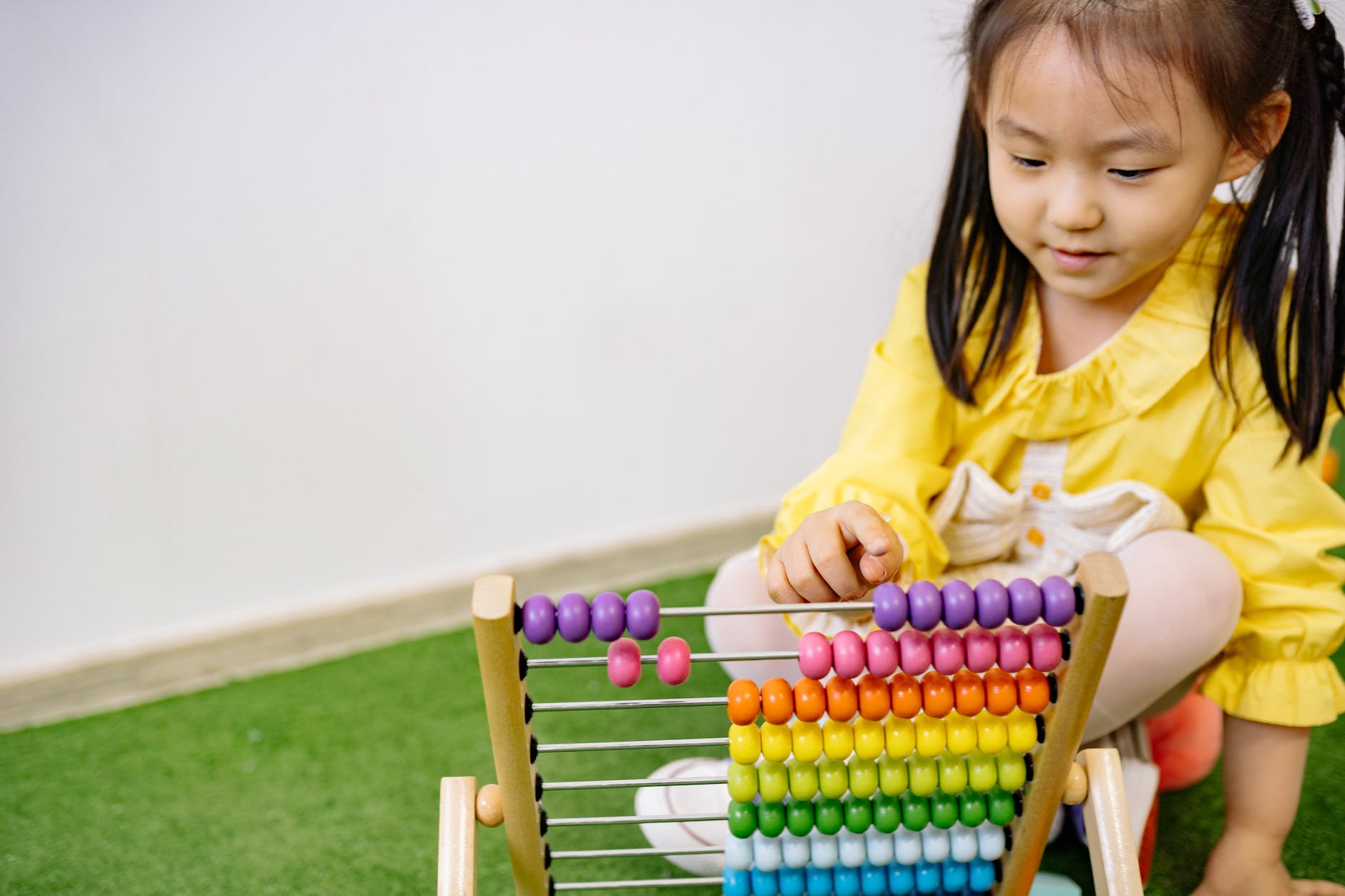 Girl in yellow dress playing with abacus anger
