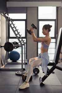 Photo of woman sitting and raising dumbbells gym fitness near me